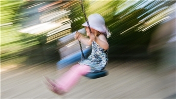 Ein kleines Mädchen schaukelt auf einem Spielplatz