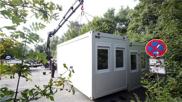 Arbeiter stellen Wohncontainer auf.