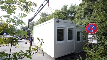 Arbeiter stellen Wohncontainer auf.