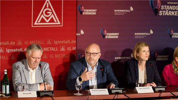 Daniel Friedrich (M), Verhandlungsführer IG Metall Küste, verkündet neben Horst Ott (l), Verhandlungsführer IG Metall Bayern, und Lena Ströbele (r), Verhandlungsführerin Nordmetall, auf einer Pressekonferenz die Einigung in den Tarifverhandlungen in der Metall- und Elektroindustrie. Arbeitgeber und Gewerkschaft haben einen Tarifabschluss für die Beschäftigten der Metall- und Elektroindustrie erzielt.