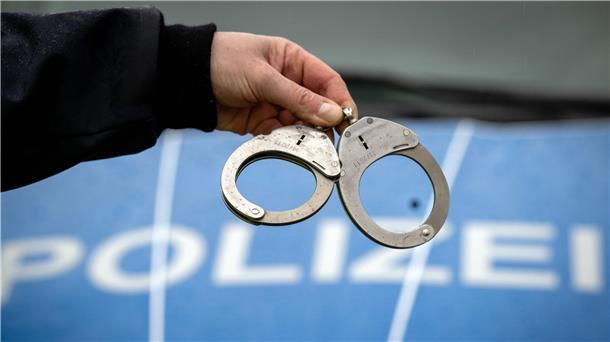 Ein Polizist hält während einer Verkehrskontrolle ein Paar Handschellen.