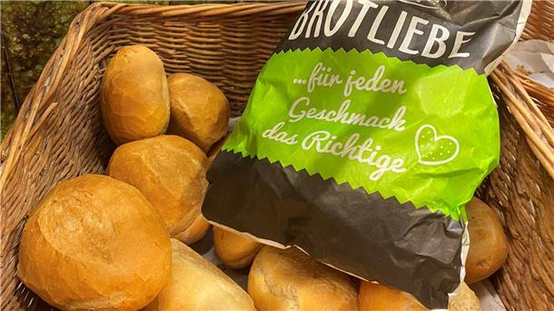 Eine gefüllte Brötchentüte liegt in einem gefüllten Brötchenkorb.