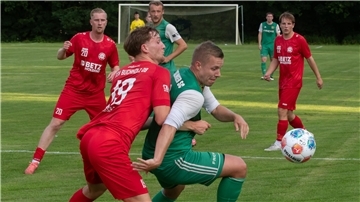 Zwei Männer in Sporttrikots kämpfen um einen Ball.
