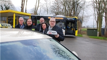 Menschen stehen vor einem Taxi und lachen in die Kamer