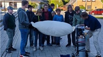 Mehrere Schüler und ein Lehrer  pumpen den Wetterballon auf.