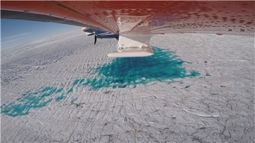 Das AWI-Forschungsflugzeug Polar 6 fliegt über den 79-Grad-Nordgletscher in Grönland. Deutlich zu erkennen sind die Schmelzwasserseen auf der Gletscheroberfläche.