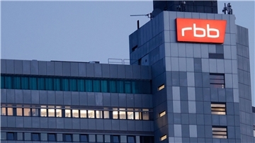 Das beleuchtete Logo des Senders Rundfunk Berlin-Brandenburg (RBB) ist an der Fassade am Sitz des Senders an der Masurenallee angebracht.
