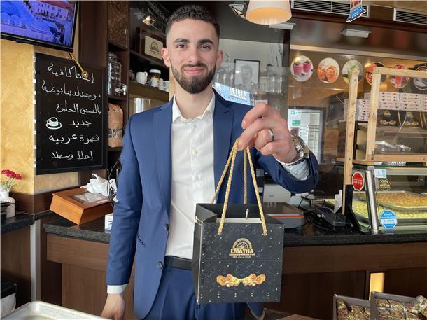 Mann im Anzug mit Tüte in der Hand in einem Laden für Gebäck