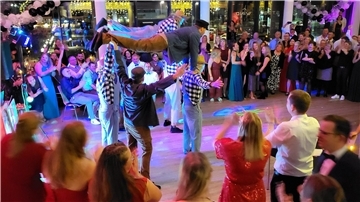 Bild von einer akrobatischen Vorführung einiger Männer und einem festlich gekleideten Publikum