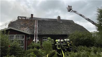 Das Feuer ist von der Gartenlaube auf das Wohnhaus übergegangen. Die Feuerwehr kämpft dagegen an, dass die Flammen auch das Haus zerstören.