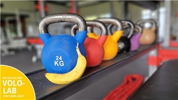 Eine Banane vor bunten Kettlebells.