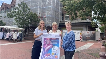 Drei Frauen mit Plakat der Volkshochschule