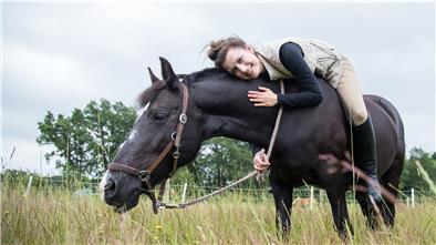 Frau auf Pferd, liegt auf dem Pferderücken