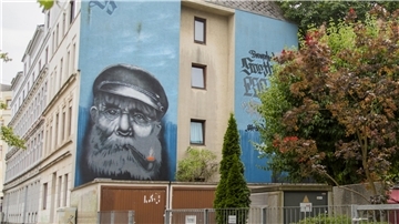 Eine Häuserfassade mit einem Graffiti, das einen alten Seemann mit Vollbart und Schiffermütze zeigt.