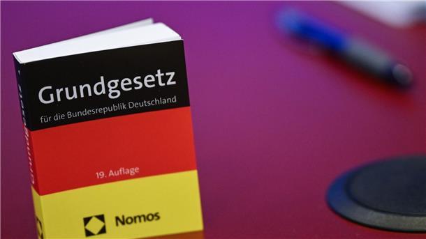 Was bedeutet das Gutachten zur AfD in Brandenburg? Das Grundgesetz in Miniatur-Ausgabe steht bei der Pressekonferenz zur AfD auf einem Tisch.