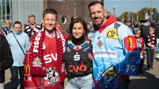 Drei Menschen in Eishockey-Trikots. 