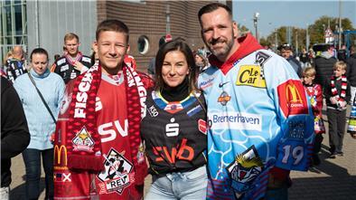 Drei Menschen in Eishockey-Trikots. 
