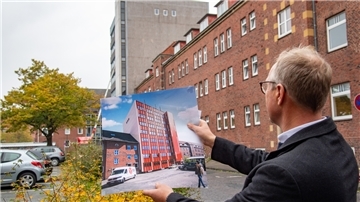 Holger Schneeburg mit einer Darstellung des künftigen Stadthauses.