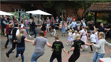 Einwohner verschiedener Generationen präsentieren auf dem „Roten Platz“ in Glinstedt den Volkstanz „Kolo“.