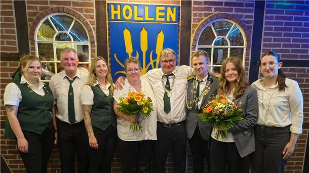 Neue Schützenkönigin in Hollen ist erst 18 Jahre alt **ALT-Text:**
Gruppenfoto des neuen Königshauses des Schützenvereins Hollen: Acht Personen, teils in Uniform, stehen vor einem Schild mit der Aufschrift „Hollen“, zwei von ihnen halten Blumensträuße.