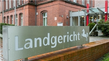 Ein Schild mit der Aufschrift Landgericht Verden steht vor einem Gebäude. 