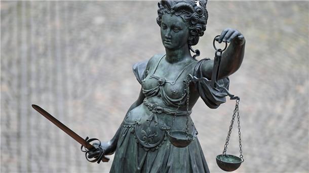 Eine Statue der Justitia hält eine Waage und ein Schwert in der Hand.