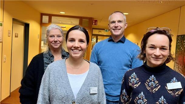 Vier Menschen lächeln in die Kamera. 