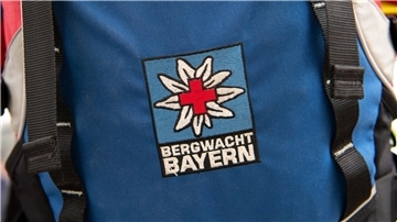 Das Logo der Bergwacht ist an einem Rucksack zu sehen. Bei Oberstdorf musste die Bergwacht nun einen Mann retten, der ohne richtige Ausrüstung und Erfahrung zwei Nächte in den Bergen verbrachte. (Archivfoto-Illustration)