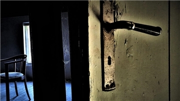 Eine halb geöffnete alte Tür gewährt einen Einblick in ein verlassenes Zimmer