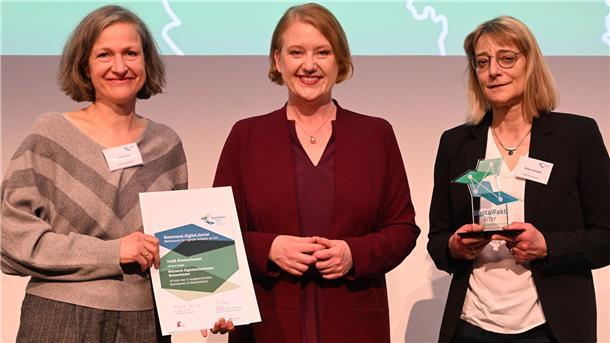 Bremerhavener Digitalprojekt gewinnt bundesweiten Wettbewerb - Jury lobt Nachhaltigkeit Gruppenfoto mit drei Frauen. Die Frau links hält eine Urkunde in der Hand, die Frau rechts eine Auszeichnung. Das Netzwerk Digitalambulanzen Bremerhaven zählt zu den Gewinnern des bundesweiten Wettbewerbs „Kommunal.Digital.Genial“: Heike Eulitz (links) und Verena Springer (rechts) nahmen die Auszeichnung im Beisein von Bundesseniorenministerin Lisa Paus in Mannheim entgegen.
