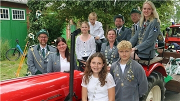 Männer, Frauen und Kinder haben sich an einem alten Trecker zum Foto aufgestellt