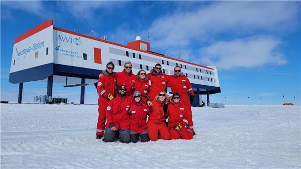 Das neunköpfige Überwinterungsteam posiert vor der Forschungsstation Neumayer III in der Antarktis.