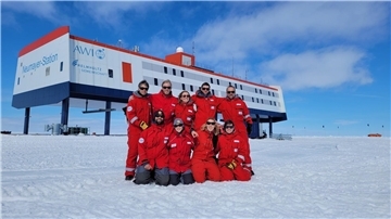 Das neunköpfige Überwinterungsteam posiert vor der Forschungsstation Neumayer III in der Antarktis.