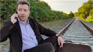Ein Mann sitzt auf Gleisen und telefoniert mit einem Handy. Das piccolo teatro Haventheater zeigt "Nächste Station: Abenteuer". In dieser Uraufführung spielt Stefan Wilde die Rolle des Amadeus. 