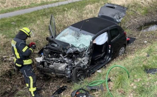 Ein zerstörtes Auto liegt auf einem Grünstreifen