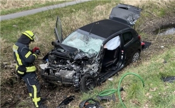 Ein zerstörtes Auto liegt auf einem Grünstreifen