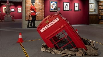 Das Smartphone hat ihnen den Garaus gemacht: Die Telefonzellen sind aus Londons Stadtbild fast verschwunden. Kein Wunder, dass Banksys Telefonzelle leidet, sie wurde mit einer Spitzhacke beschädigt. Und die Wache vorm Buckingham Palace guckt zwar interessiert, aber pinkelt in die Ecke. 
