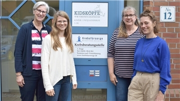 Vier Frauen stehen nebeneinander vor einem Schild.