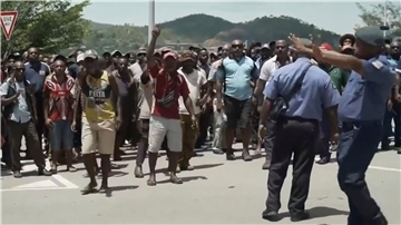 Das Videostandbild zeigt zwei Polizisten neben einer aufgebrachten Menschenmenge in Port Moresby.