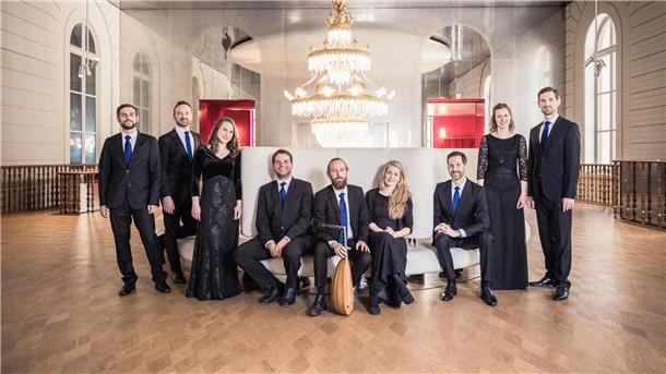 Wieso das Musikfest Bremen bald in der Wesermarsch gastiert Neun Musiker stehen in schicker schwarzer Kleidung in einem festlichen Saal mit Kronleuchter nebeneinander.