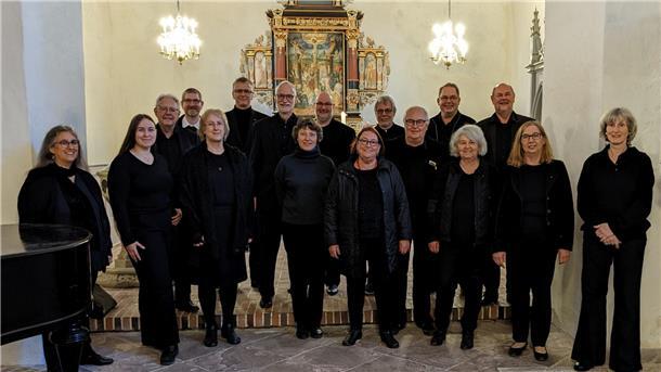 Sängerinnen und Sänger des Vokalensembles Wesermarsch stehen vor dem Altar.