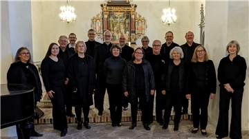 Sängerinnen und Sänger des Vokalensembles Wesermarsch stehen vor dem Altar.