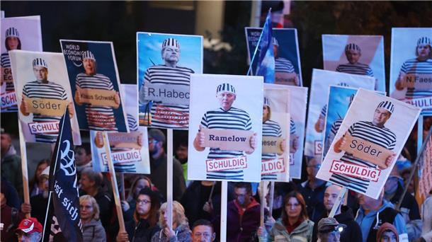Krieg und Krisen bestimmten Einheitsfeier in Erfurt Demonstranten in Gera halten Plakate mit Politikern in Häftlingskleidung hoch.