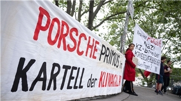 Demonstranten mit Plakaten vor Beginn der Porsche-Hauptversammlung in Stuttgart.