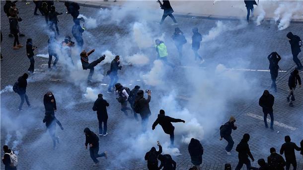 Demonstranten treten während des Protestes in Paris Tränengaskanister weg.
