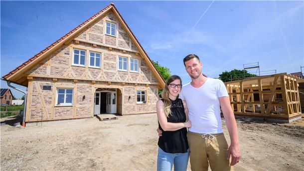 Denise und Thiemo Merz stehen vor ihrem neuen Fachwerkhaus in einem Neubaugebiet in Sehnde-Rethmar in der Region Hannover.