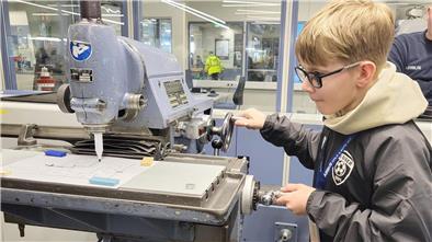 Zukunftstag 2025: 70 Schüler bei Airbus in Nordenham Ein Junge arbeitet konzentriert an einer manuellen Fräse.