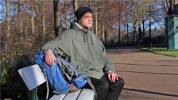 Ein Mann auf einer Parkbank am Hollersee in Bremen.