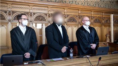 Der Angeklagte steht vor Beginn des Berufungsverfahrens vor dem Bremer Landgericht mit seinen Anwälten im Gerichtssaal.