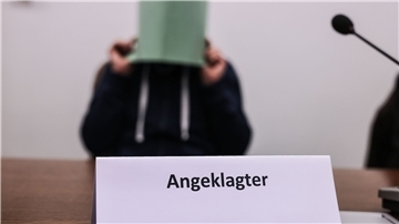 Der Angeklagte im Missbrauchskomplex Wermelskirchen hält sich im Gerichtssaal eine Mappe vor das Gesicht.
